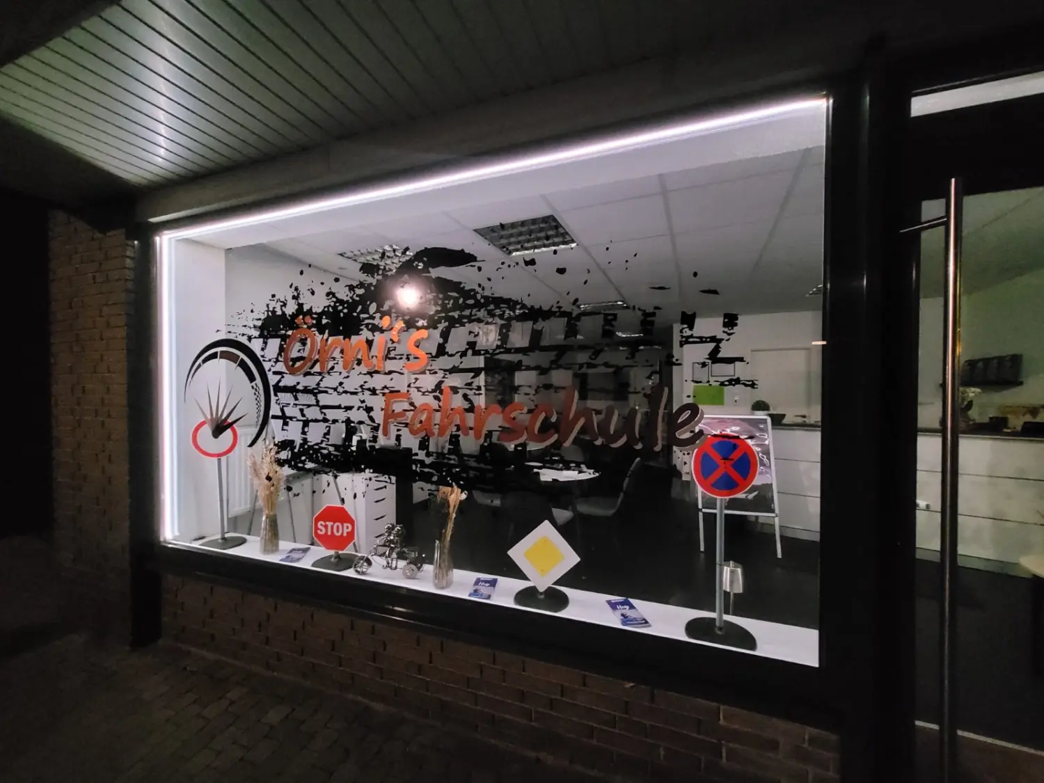 Beleuchtetes Schaufenster von Örni’s Fahrschule bei Nacht